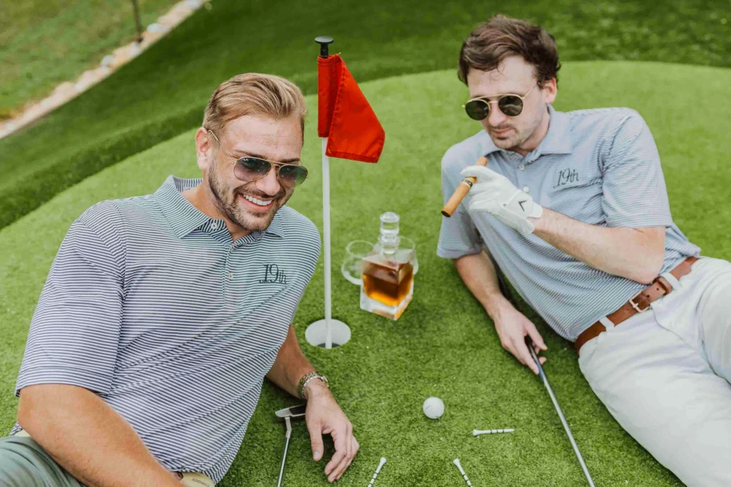 Owners of 19th At The Warehouses relax on indoor golf putting green with bourbon & cigars